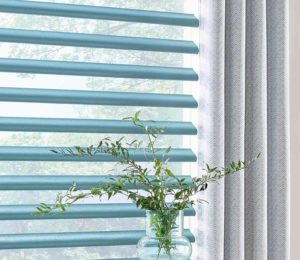 detail of blue piroutte window shades and designer drapes next to house plants