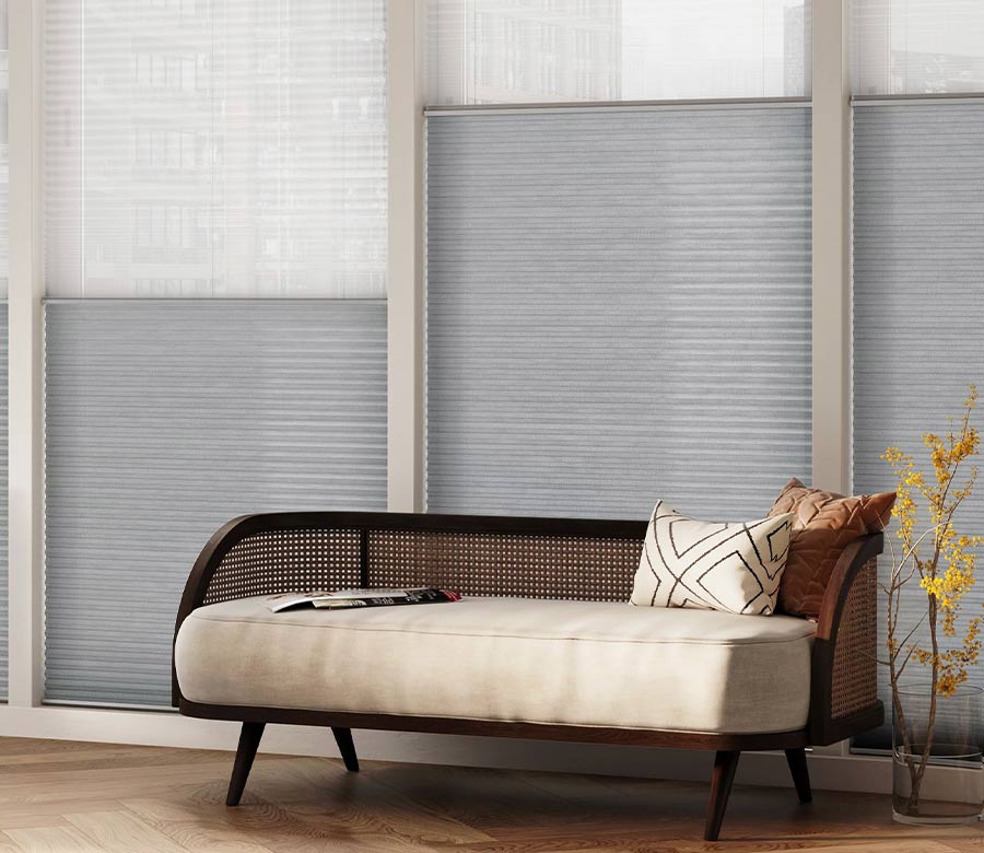 dual cellular honeycomb window shades in front of a settee