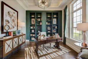 A neutral office space with a green built-in bookshelf on the back wall.