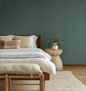 Teal green wall with a bed and nightstand pushed up against the wall