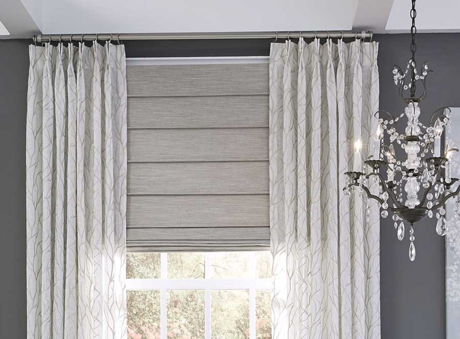 Pinch Pleat Drapery with Custom Roman Shade in a dark gray room with a nice chandelier