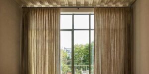pinch pleat drapery that is on either side of floor to ceiling dark trim windows