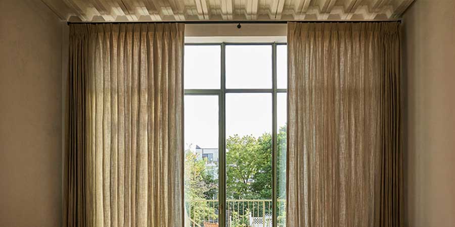 pinch pleat drapery that is on either side of floor to ceiling dark trim windows