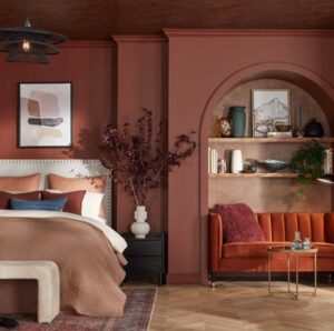 A dark red wall with a bed and nightstand against the wall